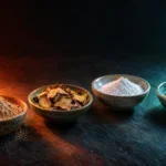 Four ceramic dishes of ashwagandha powder, rhodiola root, magnesium powder and softgels lit from tense red to calm teal light
