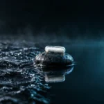A magnesium capsule on a dark stone where choppy water turns perfectly still